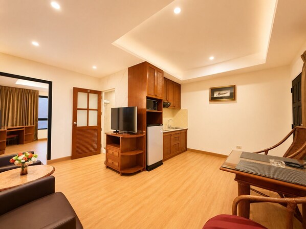 Un espacio habitable compacto con kitchenette, comedor y zona de estar con televisor.