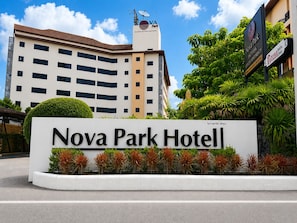 Placa do Hotel Nova Park, com um edifício moderno ao fundo.