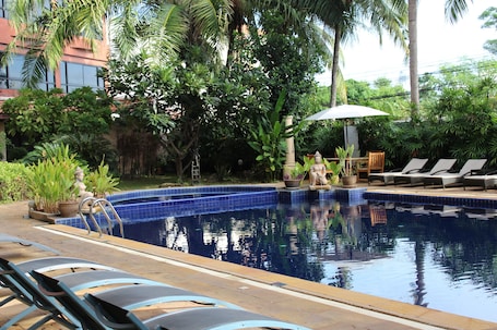 Una piscina al aire libre, sillones reclinables de piscina