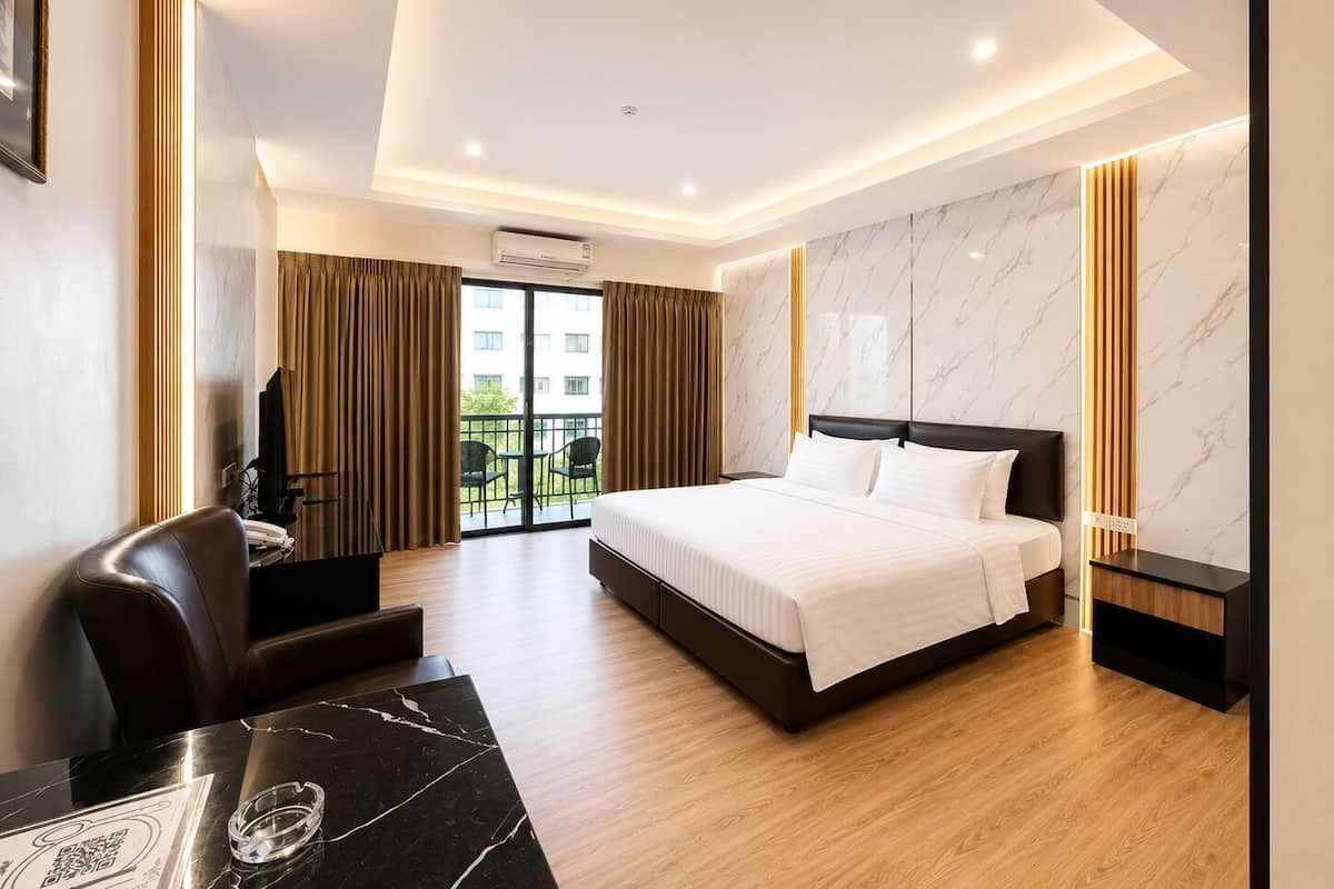 A hotel room with a bed, a desk, a chair, a TV, and a balcony with curtains.