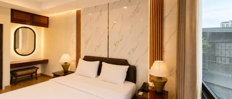 A hotel room with a large bed, bedside tables with lamps, a mirror, and a view of the city.