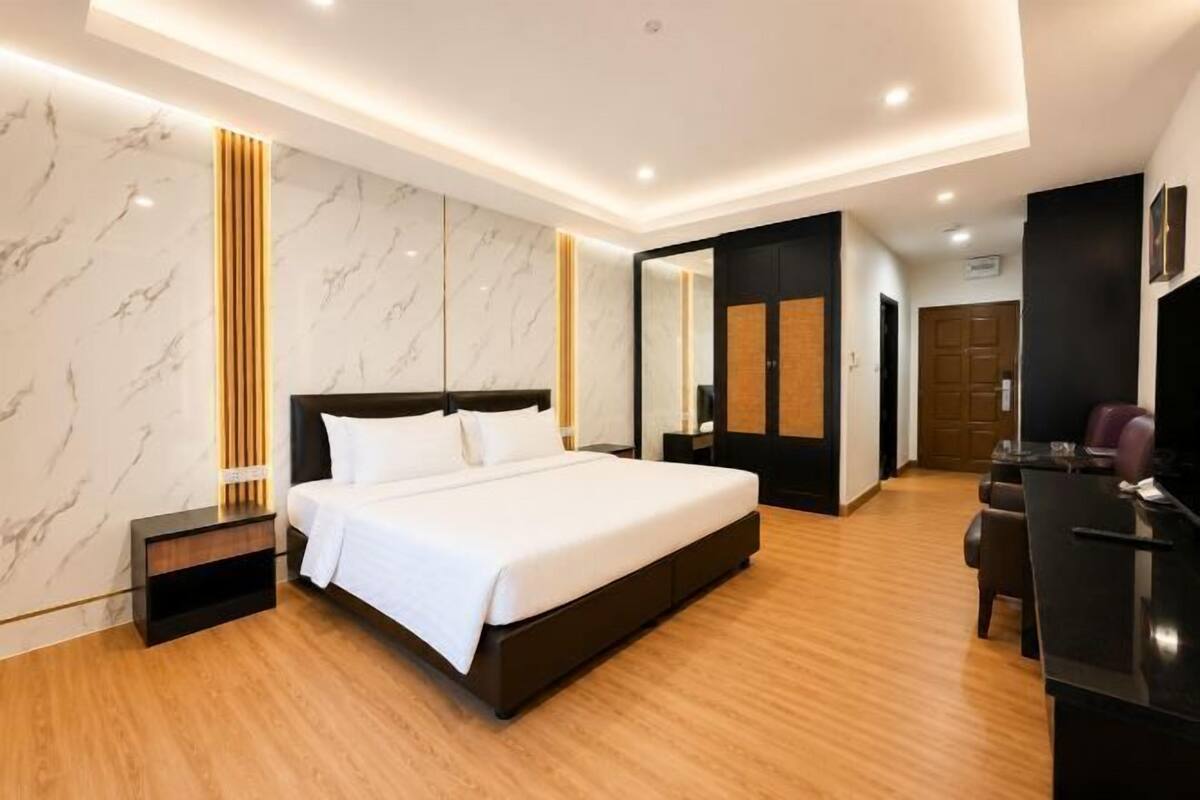 A modern hotel room with a large bed, a desk, and a mirror.