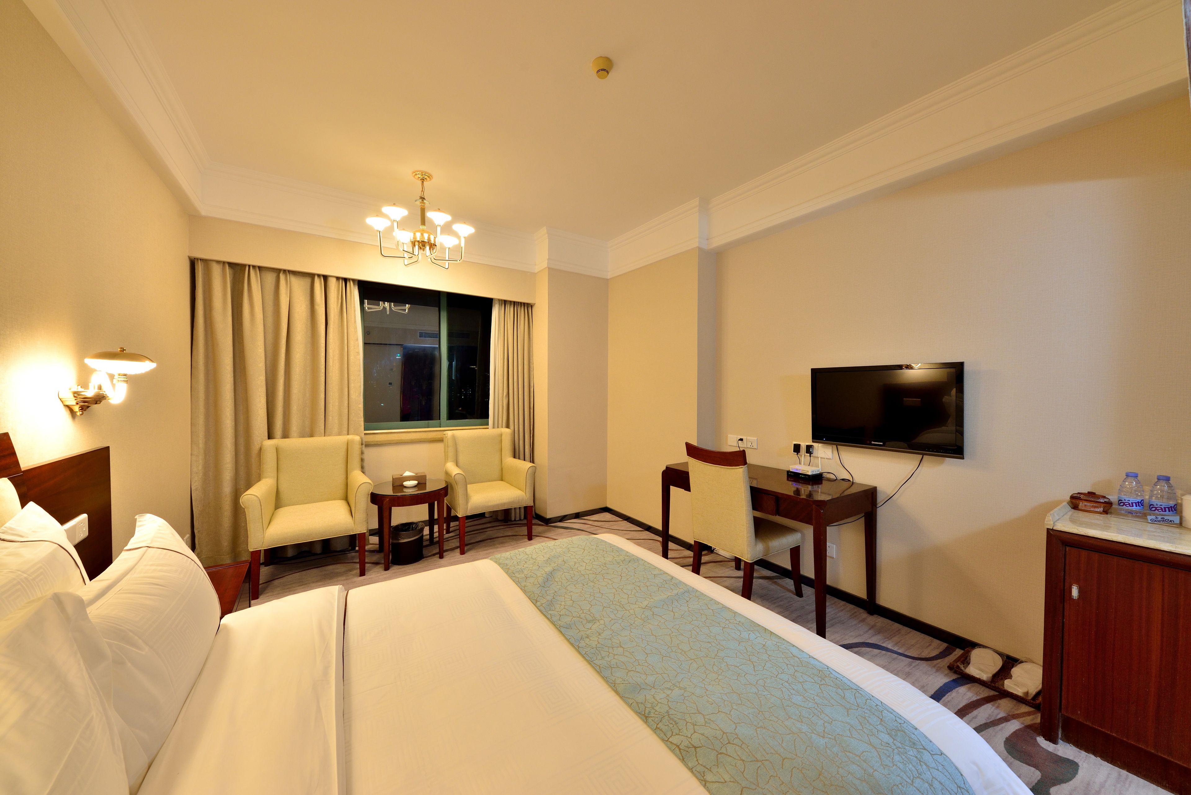 Una habitación de hotel con una cama grande, dos sillones, un escritorio, un televisor y un minibar.