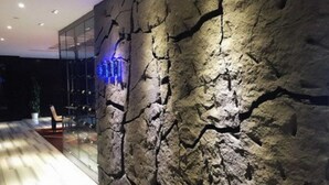 A modern interior with a textured wall and a glass partition.