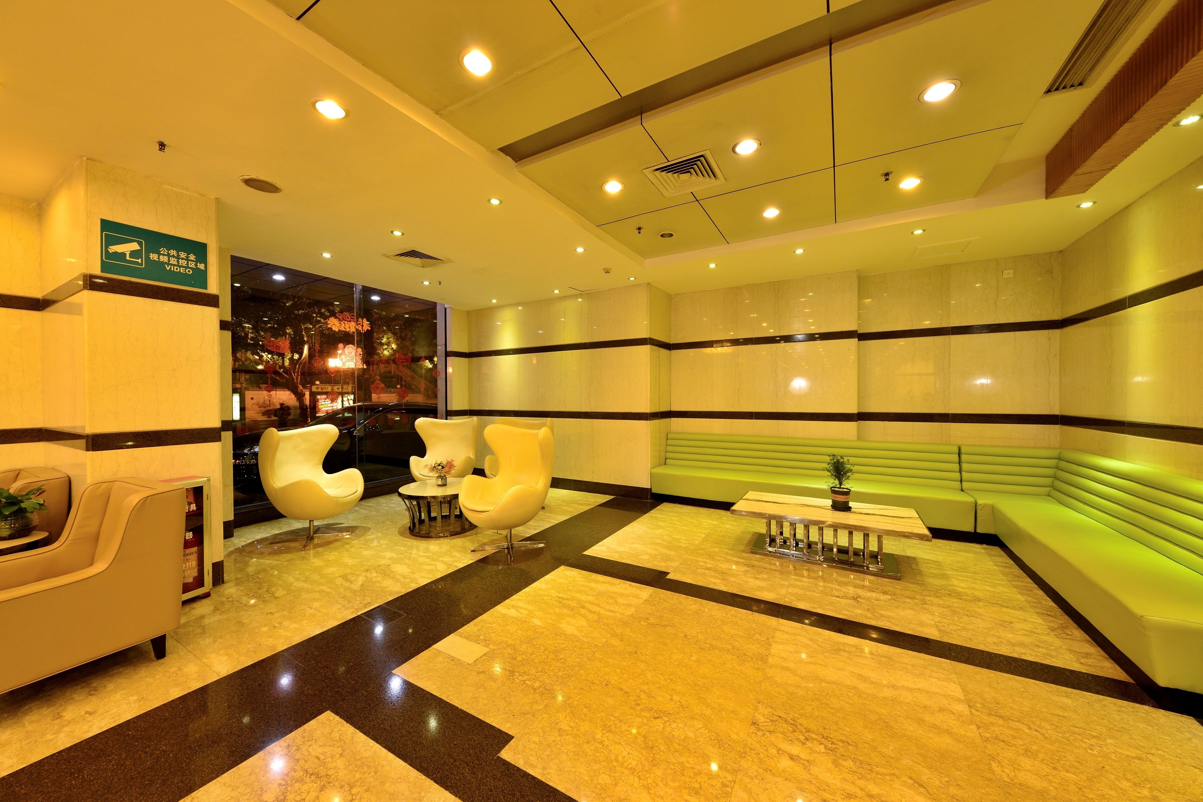 A lobby with a reception desk, seating area, and a green sofa.