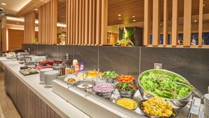 Een buffet met diverse gerechten, waaronder salades, fruit en granen.
