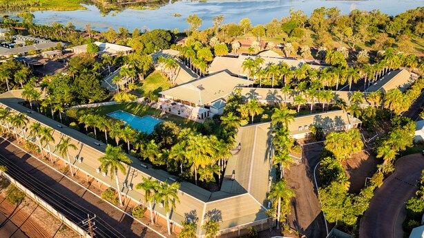 Vista aerea di una zona residenziale con case, una piscina e una grande distesa d'acqua sullo sfondo.