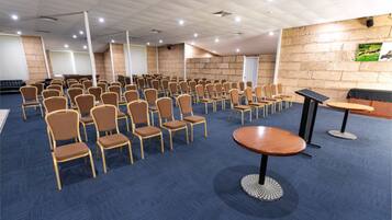 Una sala conferenze con file di sedie, un palco e uno schermo per proiettore.