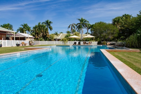 Una piscina al aire libre, sombrillas, sillones reclinables de piscina