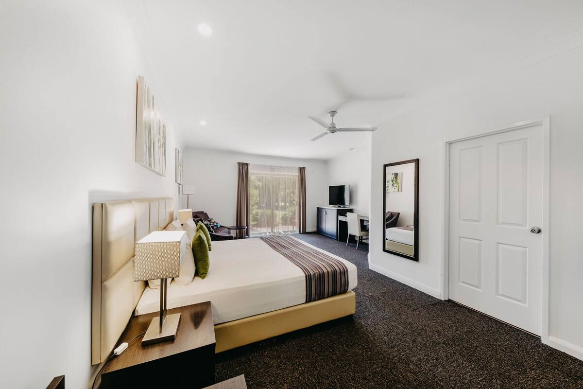 Una habitación de hotel moderna con una cama grande, un escritorio, un televisor y un ventilador de techo.