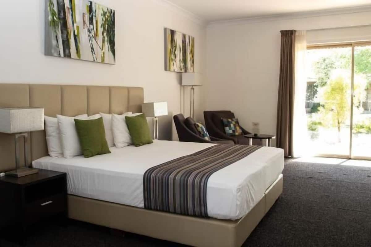 Habitación de hotel con una cama grande, un escritorio, una silla y vistas al exterior.