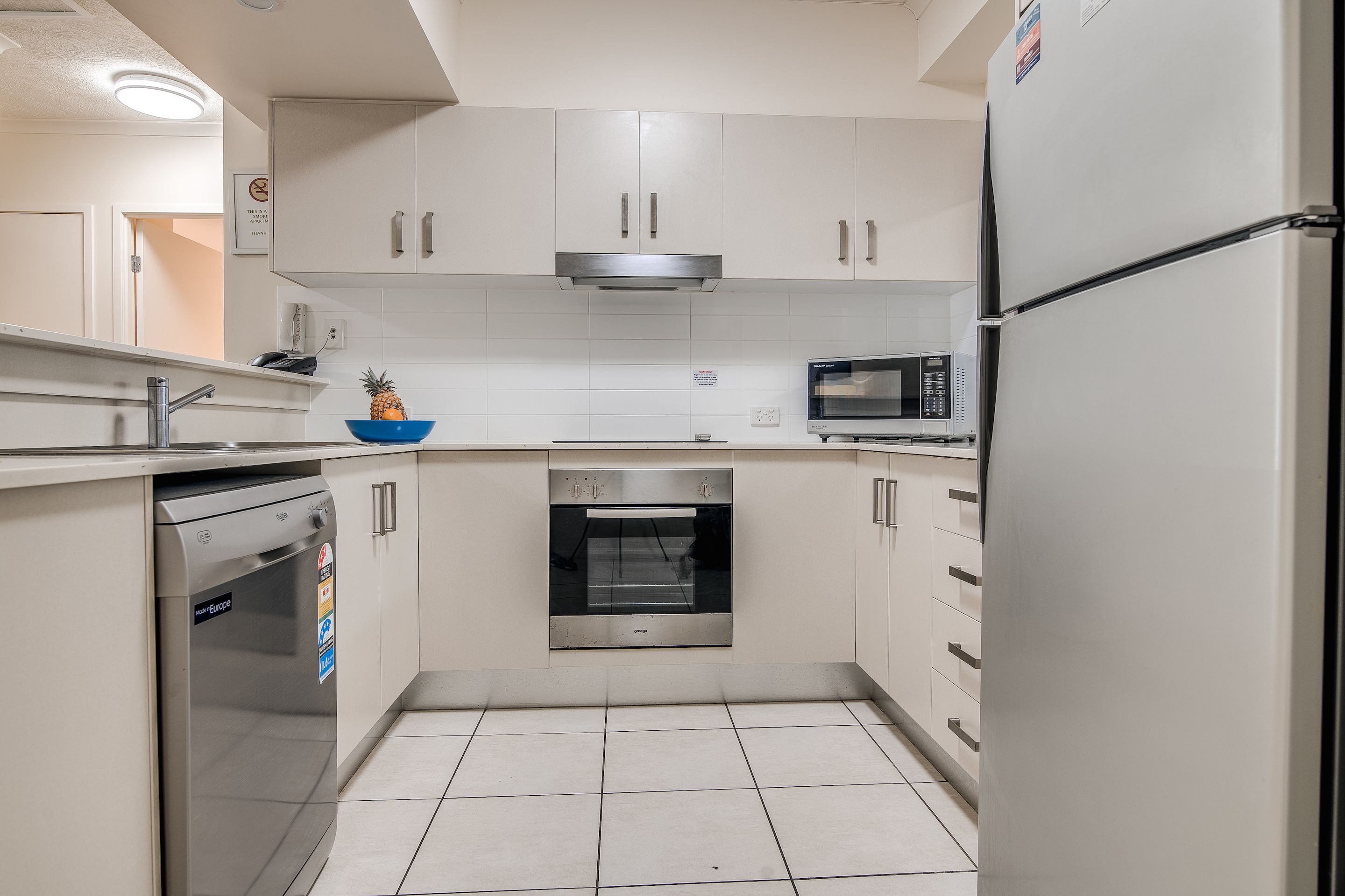 A modern kitchen with white cabinets, a built-in oven, a microwave, and a dishwasher.