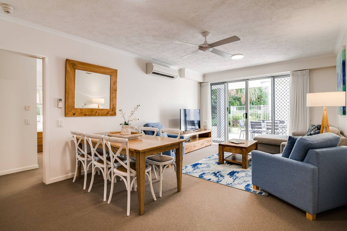 A spacious living room with a dining area, a sofa, and a ceiling fan.