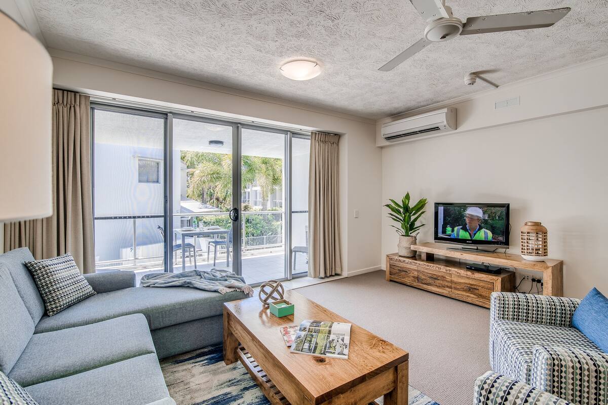 A modern living room with a grey sofa, a wooden coffee table, and a television.
