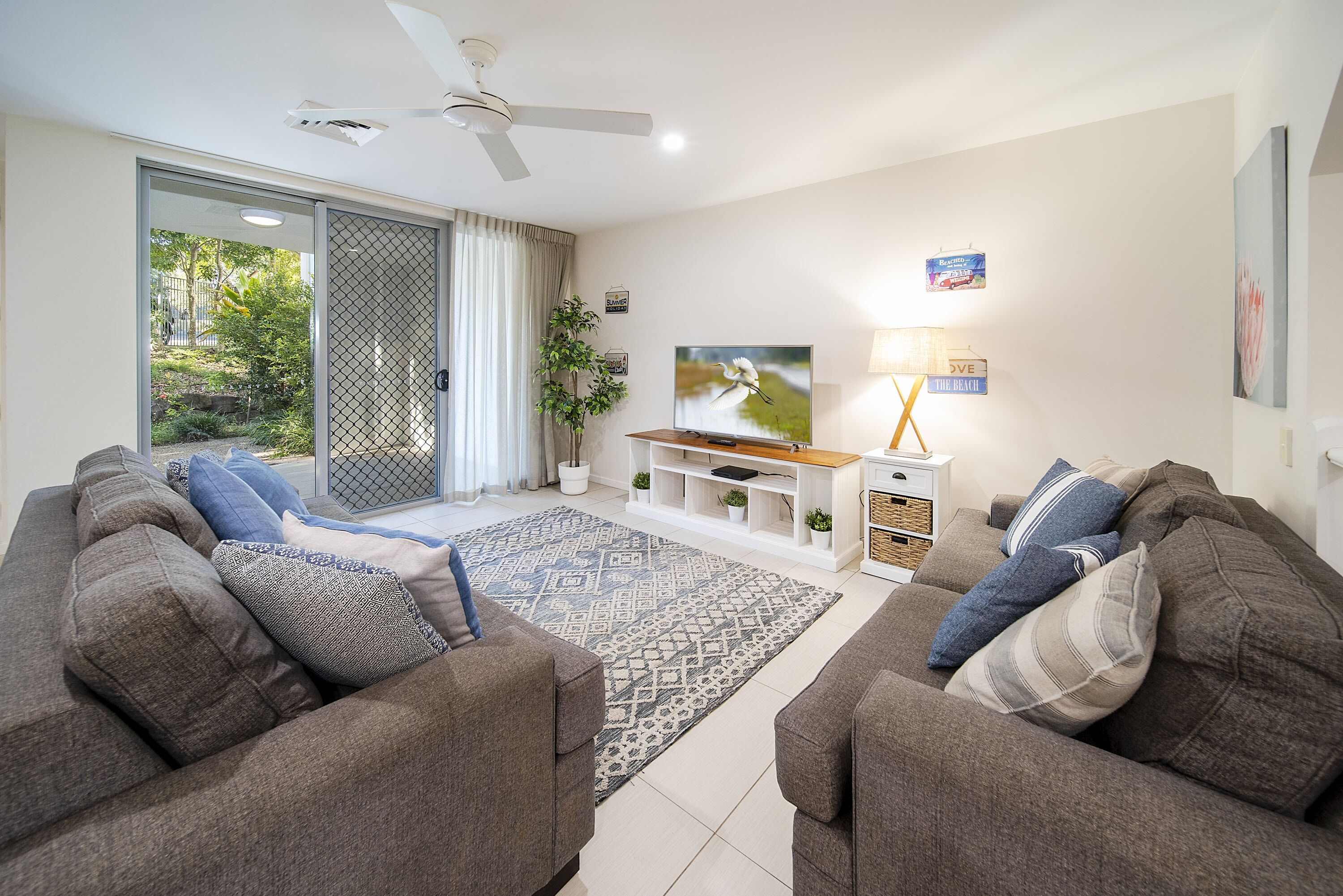 A modern living room with two sofas, a TV, and a ceiling fan.