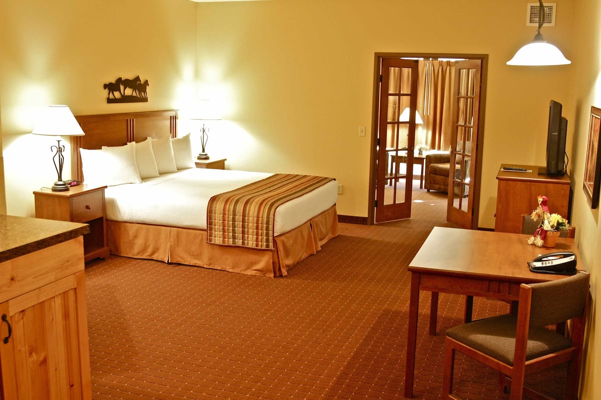 A hotel room with a bed, bedside tables, a desk with a chair, and a television.