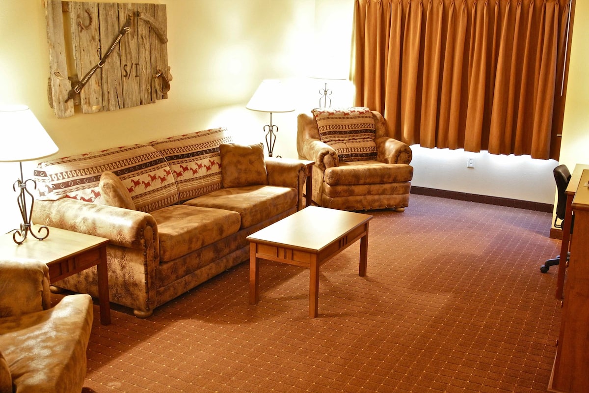 A living room with a sofa, armchairs, a coffee table, and a lamp.