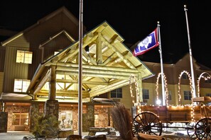A wooden building with a stone foundation, a flagpole, and a horse-drawn carriage.