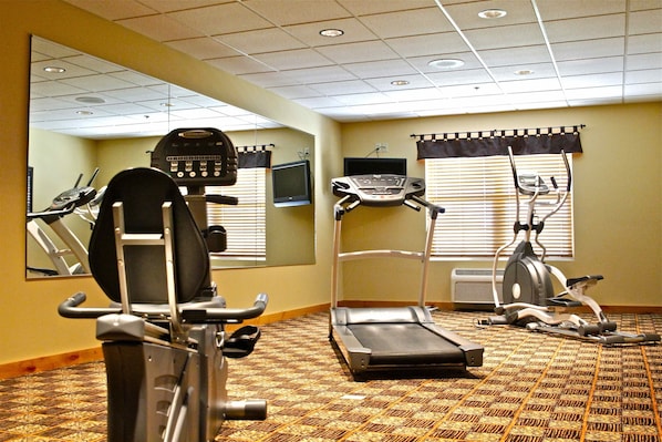 A fitness room with exercise equipment, including a treadmill, elliptical, and stationary bike.