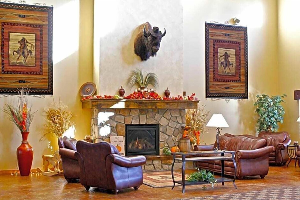 A lobby with a stone fireplace, leather sofas, framed artwork, and a mounted buffalo head.