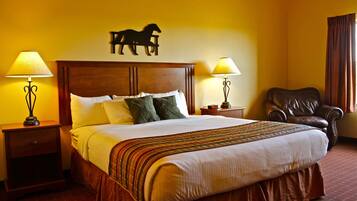 Habitación de hotel con una cama grande, dos lámparas de noche, un sillón de cuero y una silueta de caballo en la pared.