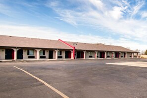 A motel with multiple rooms, a parking lot, and a clear sky.