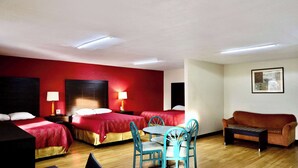 A hotel room with two beds, a dining table with chairs, a sofa, and a painting on the wall. - Rodeway Inn Pauls Valley (Pauls Valley)
