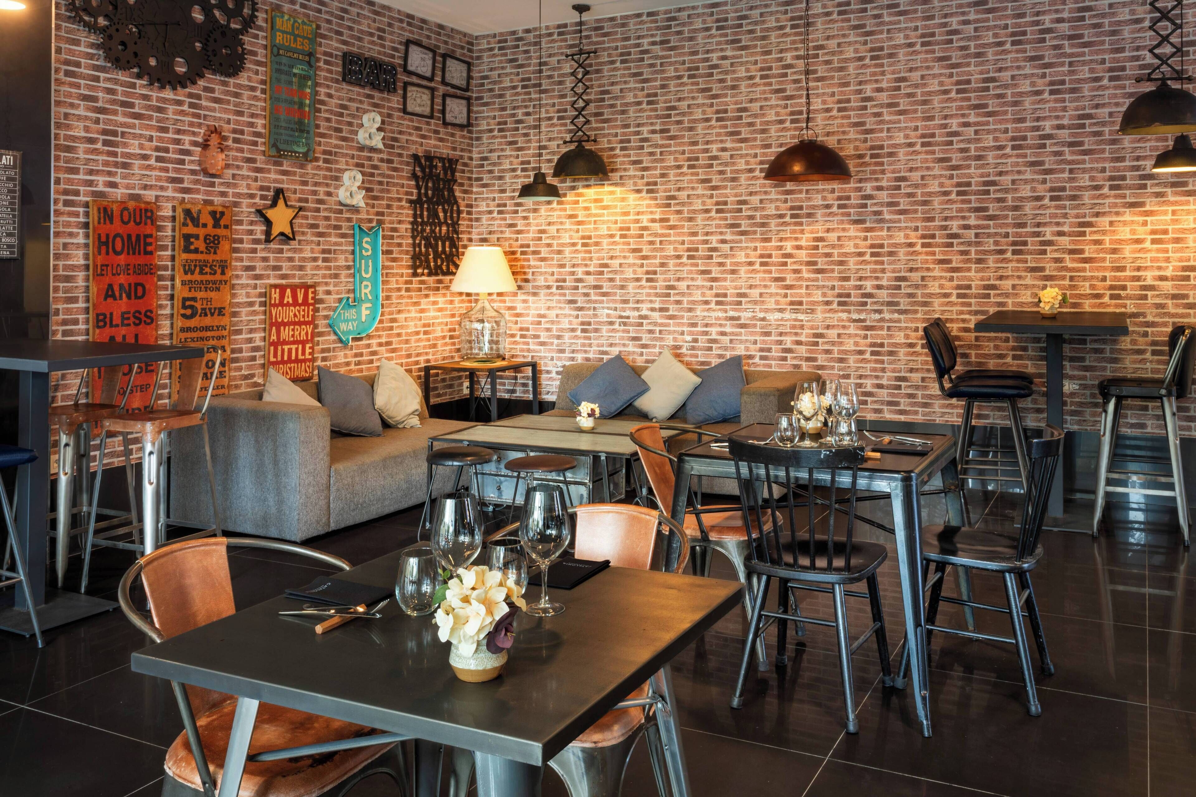 Un restaurant avec un mur en briques, plusieurs tables et chaises, et un canapé.