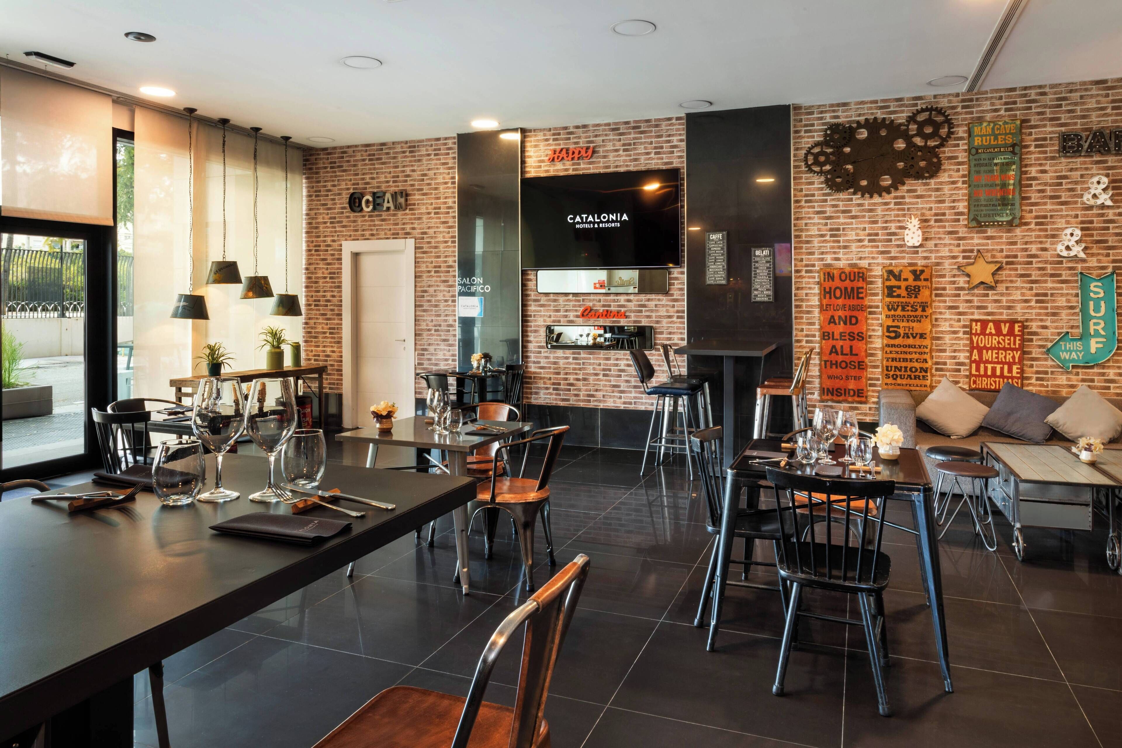 A modern restaurant with brick walls, multiple dining tables, and chairs.