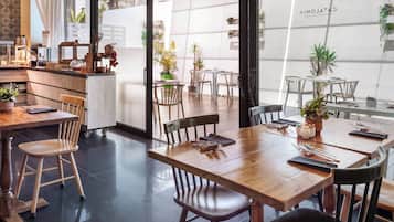Een modern restaurant met houten tafels en stoelen, een bar en potplanten.