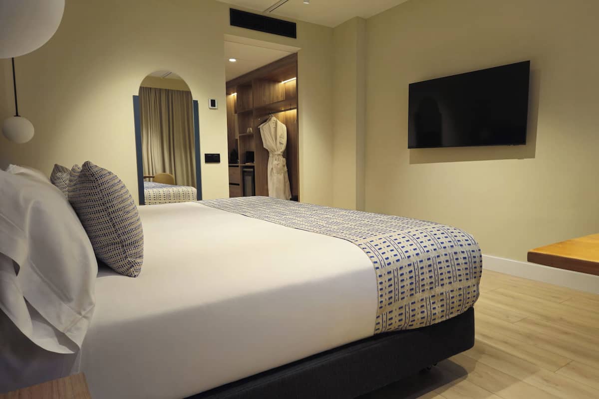 Une chambre d’hôtel moderne dotée d’un grand lit, d’une télévision à écran plat et d’un dressing.