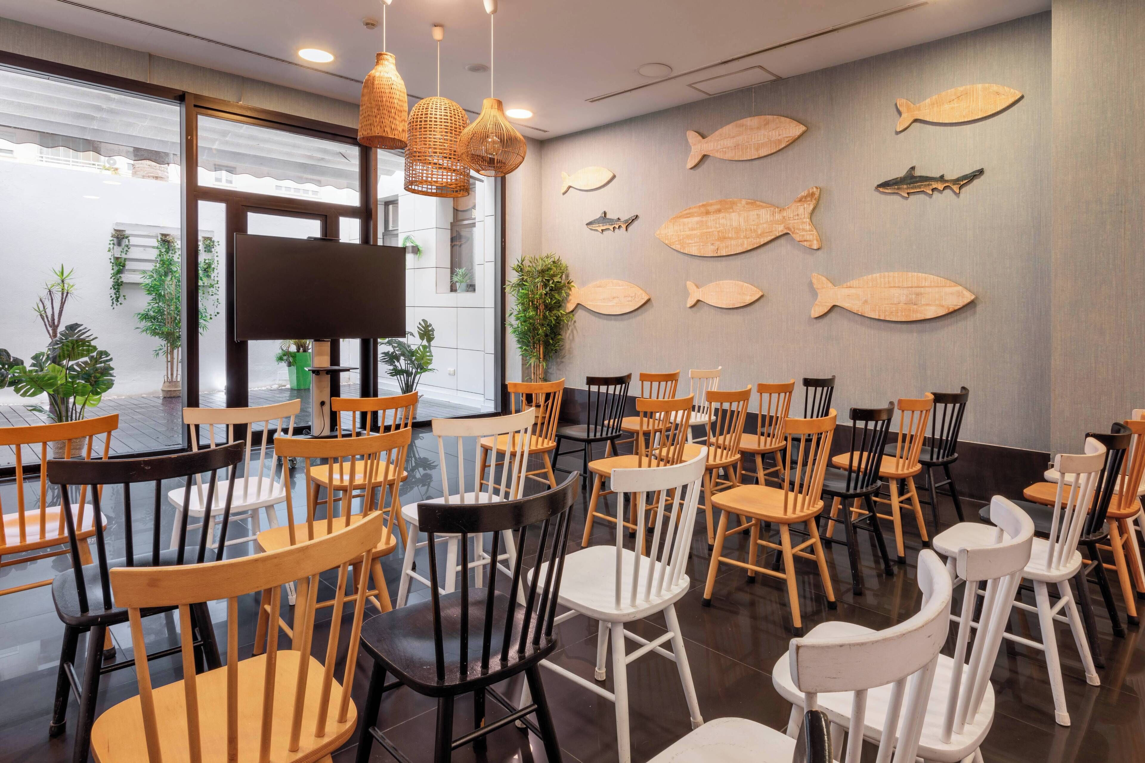 A restaurant with wooden chairs and tables, fish wall art, and hanging lights.
