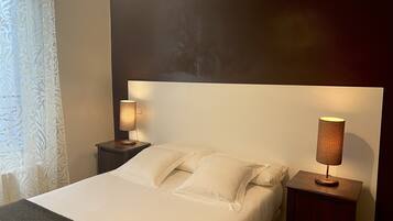 Una habitación de hotel con una cama grande, dos mesitas de noche y un cabecero.