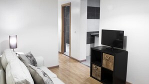 A modern living room with a white sofa, a black entertainment unit, and a wooden floor. - THC Gran Via Hostel (Madrid)