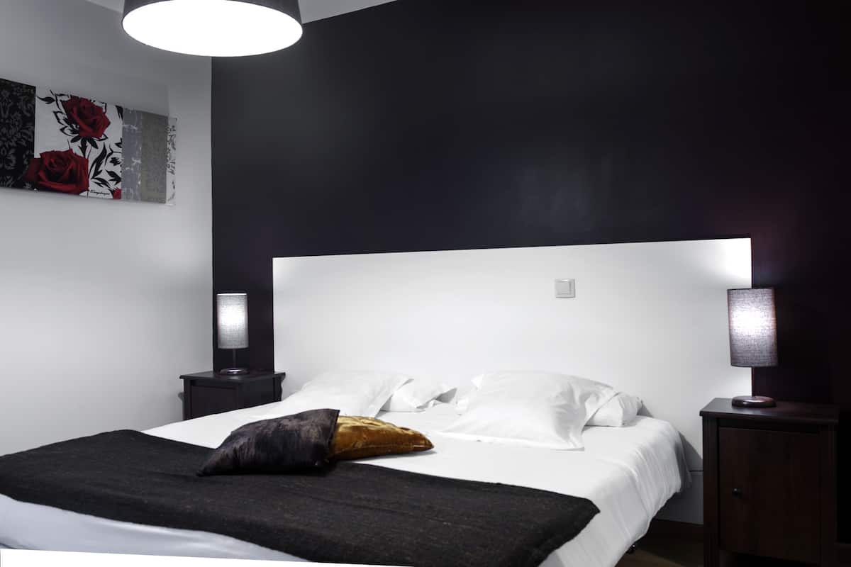 A modern bedroom with a large bed, two bedside tables, and a wall-mounted artwork.