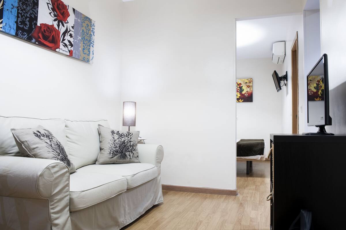 A modern living room with a sofa, a lamp, and artwork on the wall.