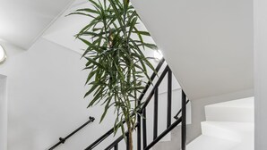 Una escalera moderna con barandilla negra, una planta en maceta y un suelo estampado.