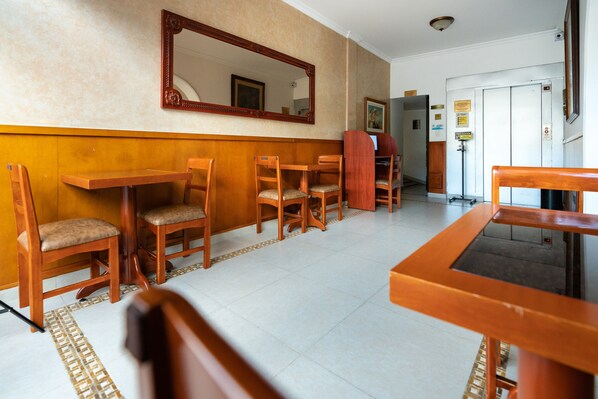 Un vestíbulo de hotel con mobiliario de madera, un espejo grande y piso de baldosas.