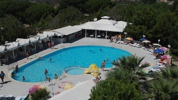 Relax by the resort's large pool surrounded by lounge chairs and umbrellas, shaded by a covered area.