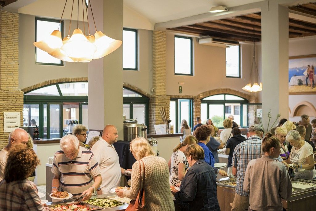 A communal dining area with people serving themselves from a buffet.