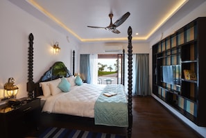 A bedroom with a four-poster bed, a ceiling fan, a nightstand with a lamp, and a bookshelf.