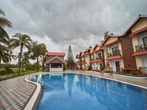 Una piscina con bordes de azulejos, rodeada por un paseo de baldosas a cuadros.
