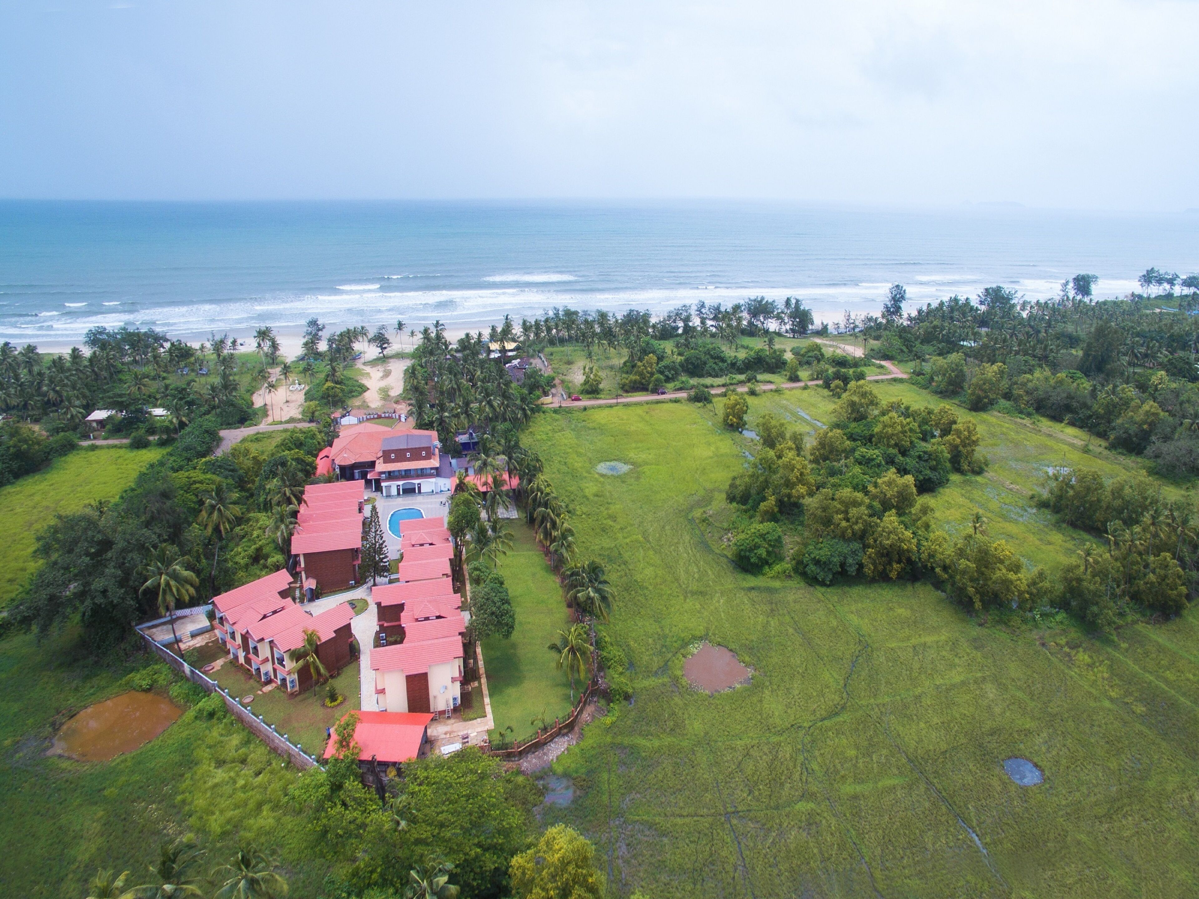 An aerial view of a resort with multiple buildings, a pool, and a beachfront.