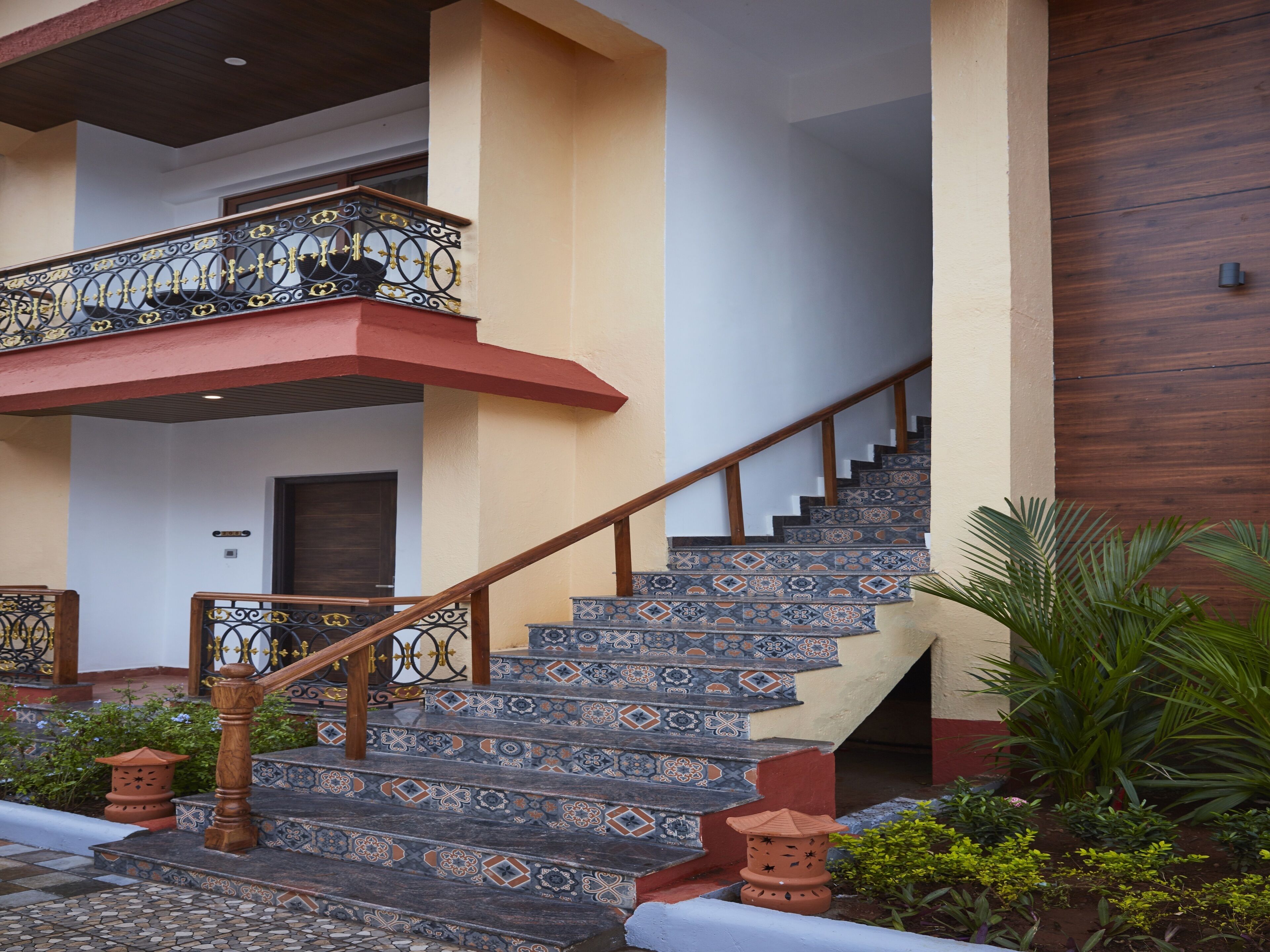 A staircase with ornate railings and patterned tiles, leading to a second-floor balcony.