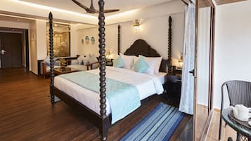 Una cama con dosel de madera, una mesita de noche con lámpara y una silla con una mesa.