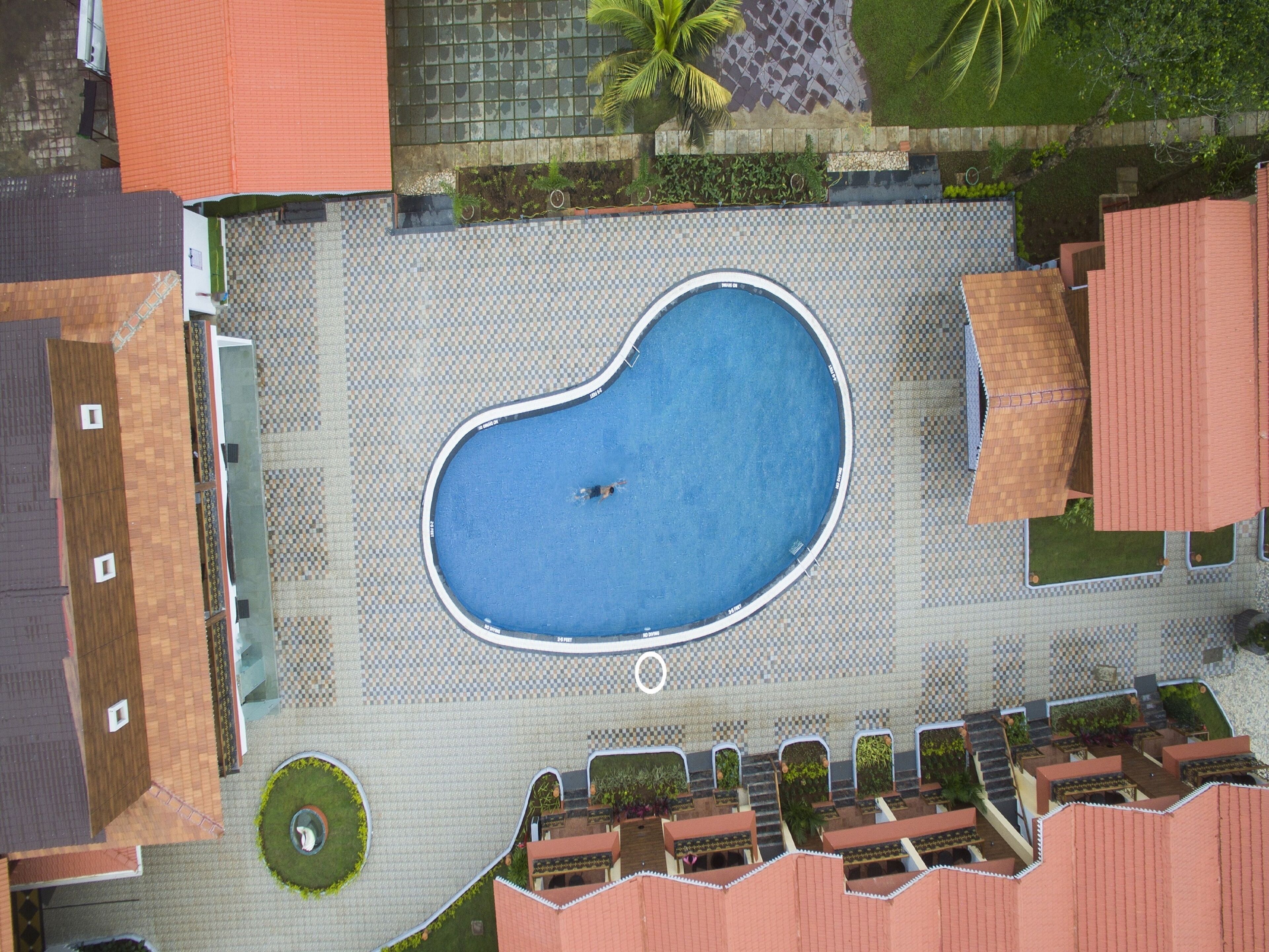 Vista aérea de un hotel con piscina, mobiliario de exterior y jardín ajardinado.