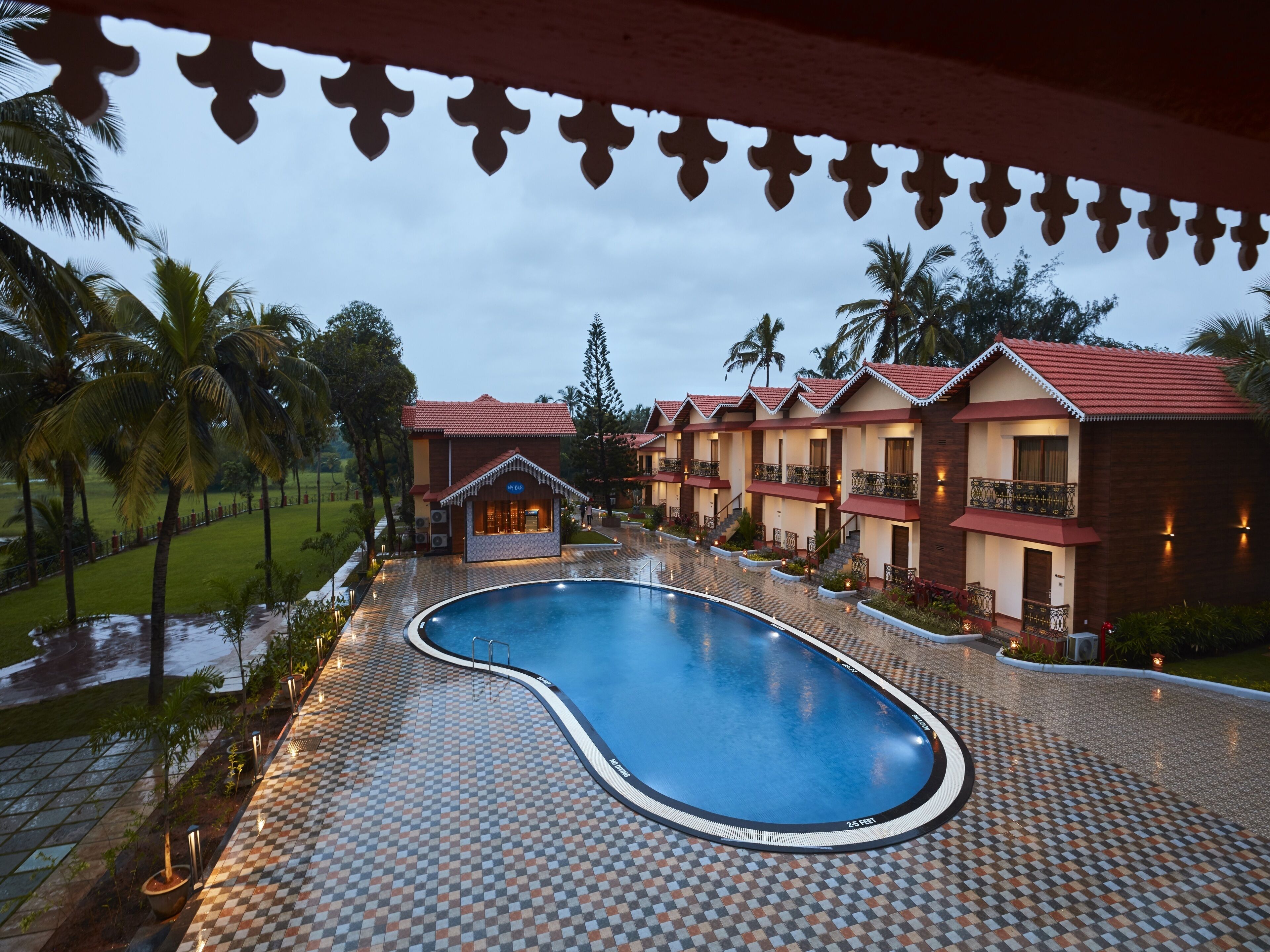 A hotel with a swimming pool, multiple guest rooms, and a garden area.