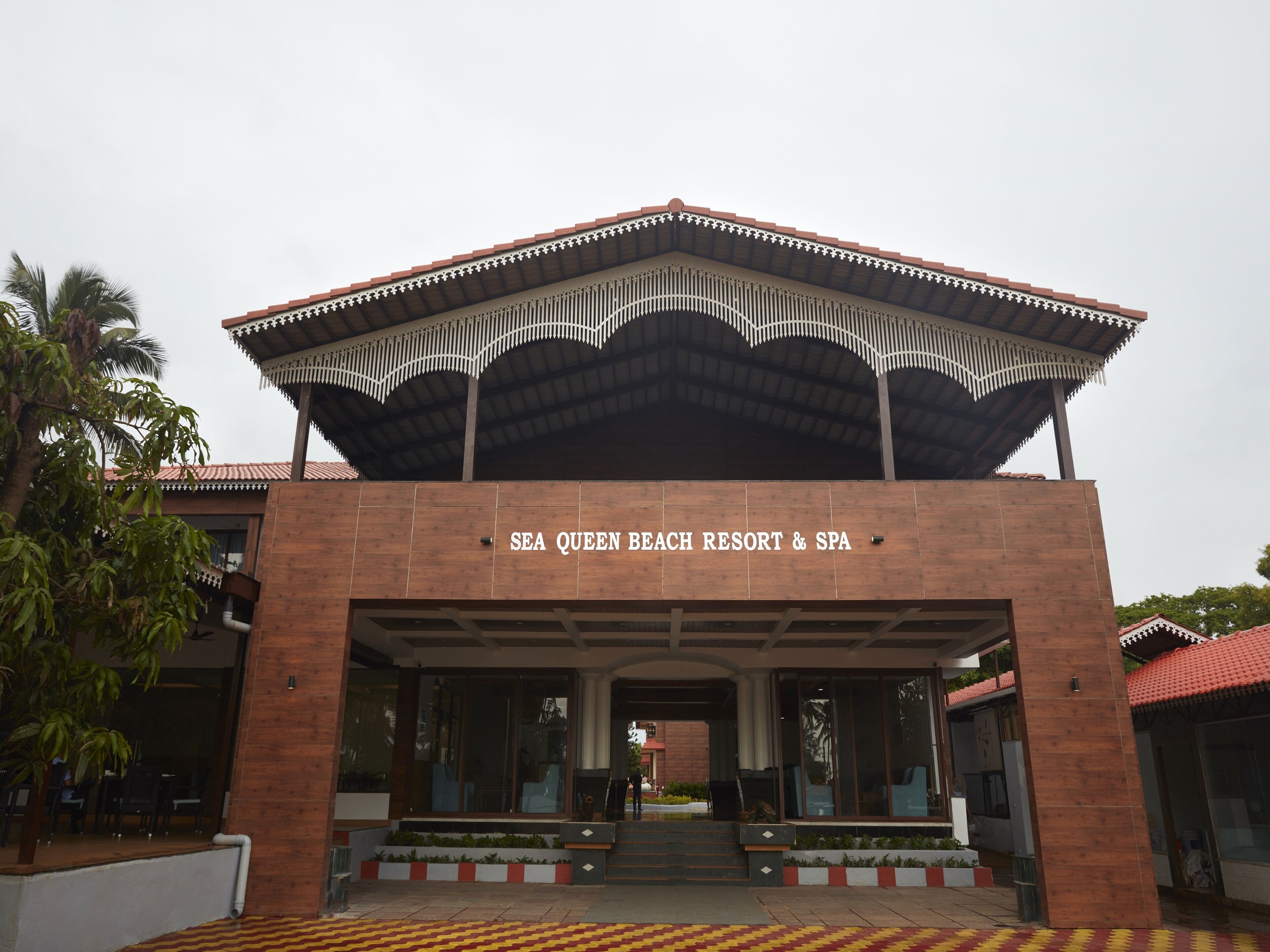 The entrance to SEA QUEEN BEACH RESORT & SPA with a covered entrance and a tiled ground.