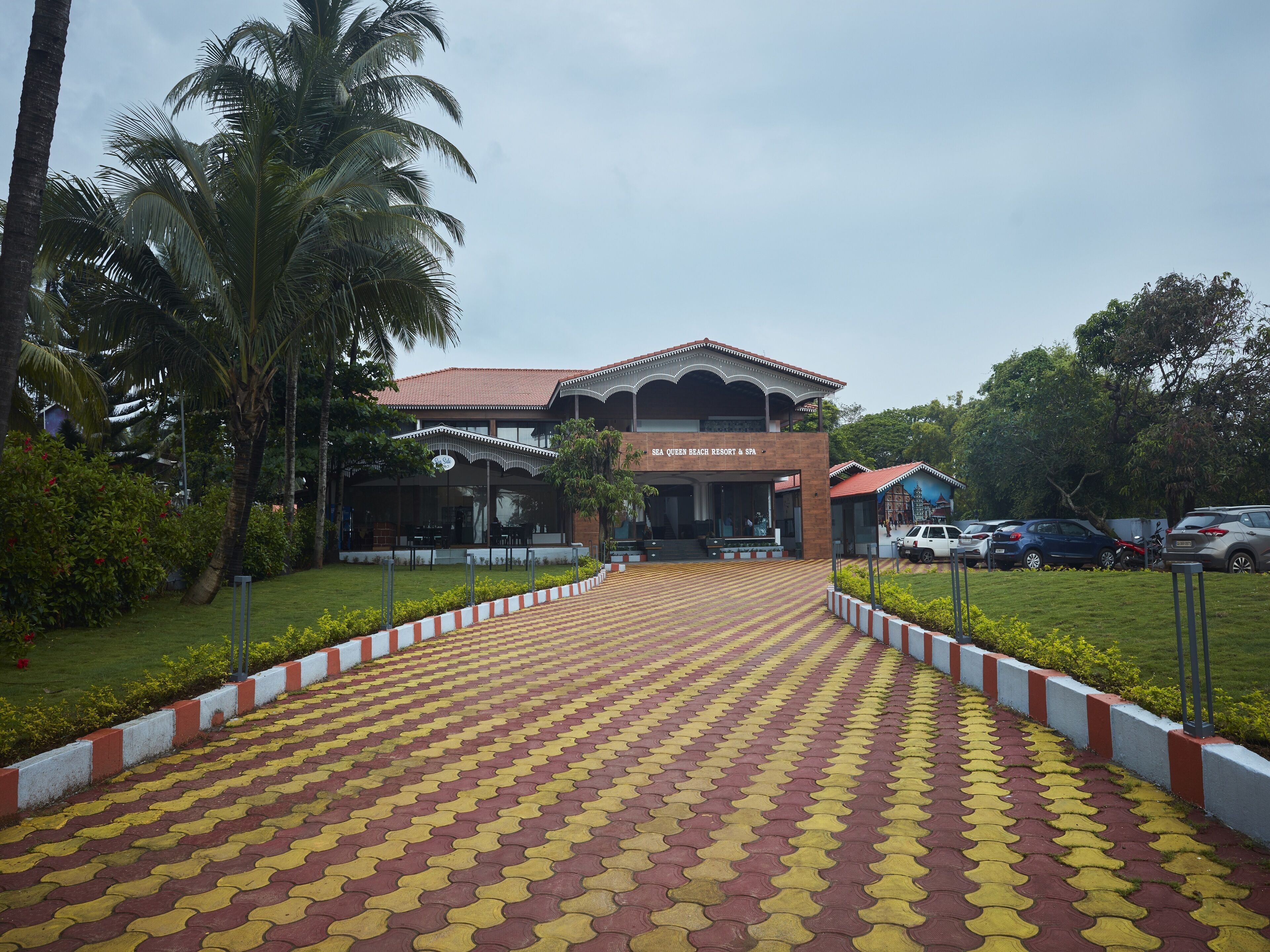 A resort entrance with a tiled pathway leading to a building labeled "SEA QUEEN BEACH RESORT & SPA".