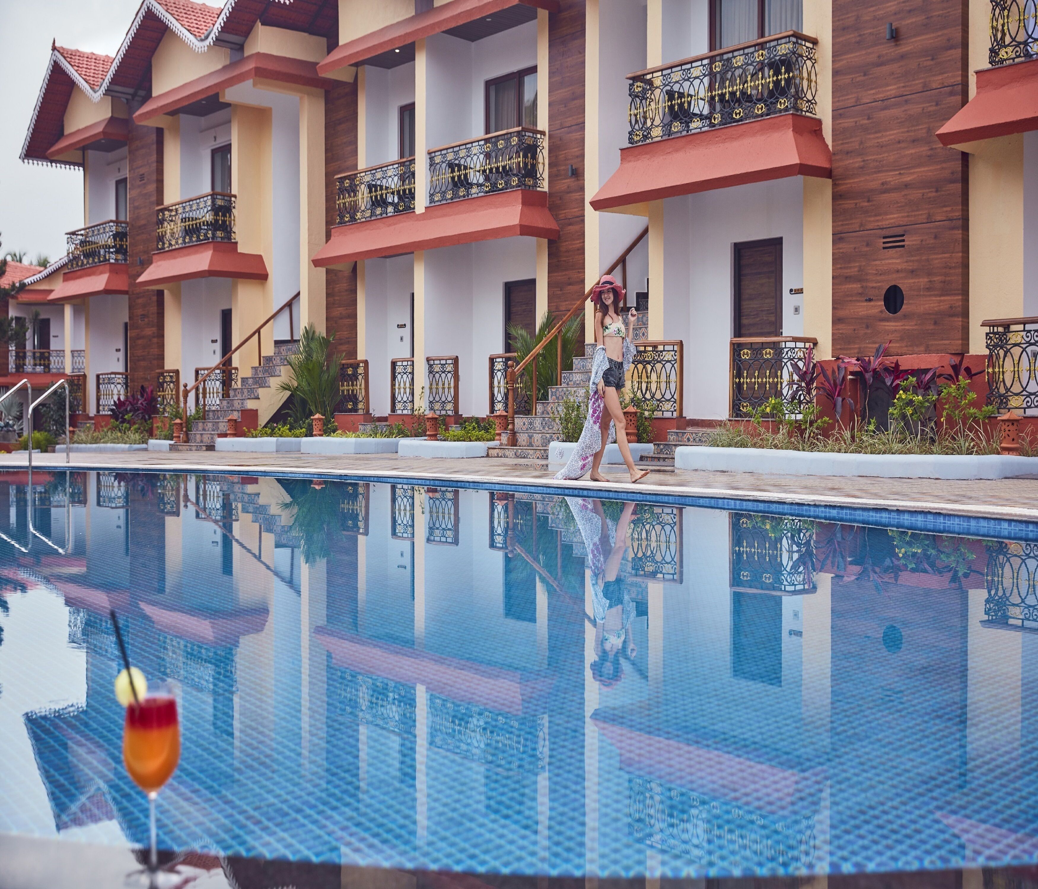 Ein Hotel mit mehreren Balkonen, einem Schwimmbad und einer Treppe zu den oberen Etagen.
